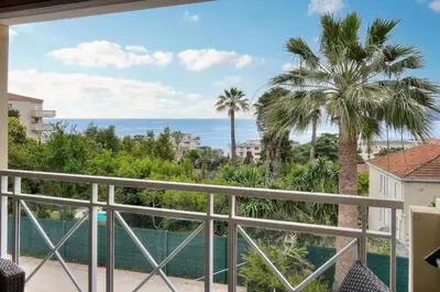 a balcony with a view of the ocean and palm trees at Eva - Piscine - Terrasse - VCA in Cannes