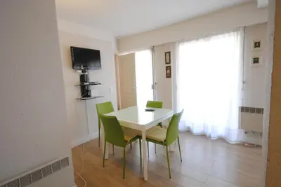 a dining room with a white table and green chairs at superbe appartement tout confort beg4012 in Cannes