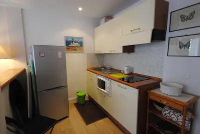 a small kitchen with white cabinets and a refrigerator at superbe appartement tout confort beg4012 in Cannes