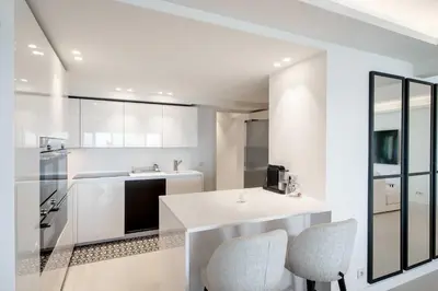 a white kitchen with a counter and chairs in it at Charming oasis with terrace 4 BD- 8P - Cannes in Cannes