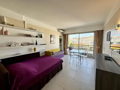 a living room with a purple bed and a table at Cannes proche Croisette - 2 pièces au calme avec terrasse in Cannes