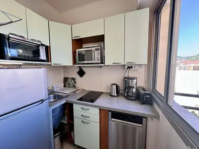 a small kitchen with white cabinets and a microwave at Cannes proche Croisette - 2 pièces au calme avec terrasse in Cannes