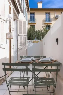 a green table with plates and glasses on a balcony at La Vela Azzurra - terrasse, clim, 15 mn à pied du Palais et plages in Cannes