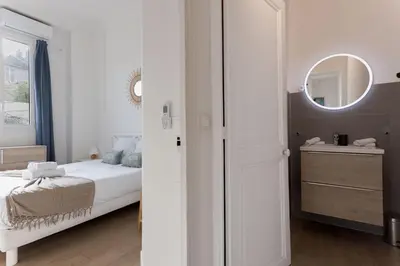 a white bedroom with a bed and a mirror at La Vela Azzurra - terrasse, clim, 15 mn à pied du Palais et plages in Cannes