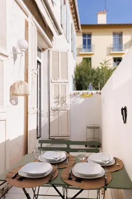 a table with plates and wine glasses on a balcony at La Vela Azzurra - terrasse, clim, 15 mn à pied du Palais et plages in Cannes