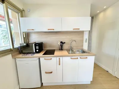 a kitchen with white cabinets and a sink at Le studio Palm Beach, Clim ,Parking, Neuf in Cannes