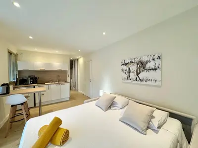 a bedroom with a white bed and a kitchen at Le studio Palm Beach, Clim ,Parking, Neuf in Cannes