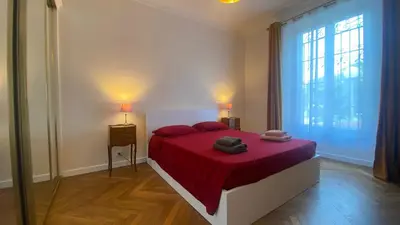 a bedroom with a bed with red sheets and a large window at Cannes - proche des plages de la célèbre Croisette in Cannes