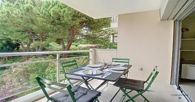 a dining table and chairs on a balcony with a view at Les Genêts - 2 chambres - Terrasse - Climatisé in Le Cannet