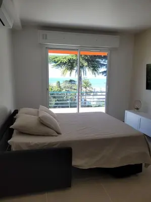 a bedroom with a large bed with a large window at Grand T2 vue mer dans résidence de standing, parking, pointe croisette in Cannes