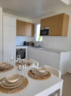 a kitchen with a table with plates and wine glasses at Grand T2 vue mer dans résidence de standing, parking, pointe croisette in Cannes