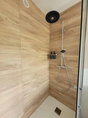 a bathroom with a shower with a wooden wall at Grand T2 vue mer dans résidence de standing, parking, pointe croisette in Cannes