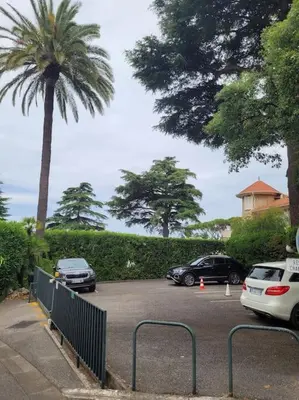 two cars parked in a parking lot with a palm tree at Grand T2 vue mer dans résidence de standing, parking, pointe croisette in Cannes