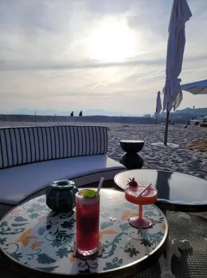 a table with a drink on the beach at Grand T2 vue mer dans résidence de standing, parking, pointe croisette in Cannes