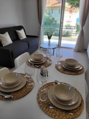 a table with plates and wine glasses on it at Grand T2 vue mer dans résidence de standing, parking, pointe croisette in Cannes
