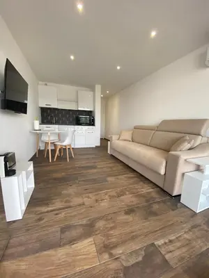 a living room with a couch and a kitchen at Studio neuf avec terrasse in Cannes