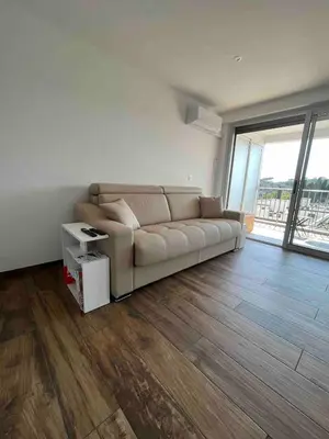 a living room with a couch and a large window at Studio neuf avec terrasse in Cannes