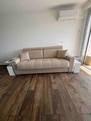 a white couch in a living room with wooden floors at Studio neuf avec terrasse in Cannes