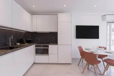 a kitchen with white cabinets and a table with chairs at Cannes Molière - Palais, Plage, Balcon, Clim et Centre ville in Cannes