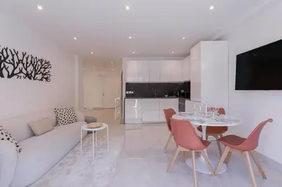 a living room with a couch and a table and chairs at Cannes Molière - Palais, Plage, Balcon, Clim et Centre ville in Cannes