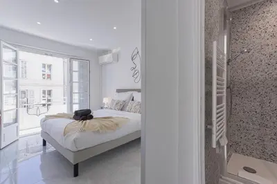 a white bedroom with a bed and a window at Cannes Molière - Palais, Plage, Balcon, Clim et Centre ville in Cannes
