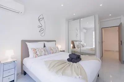 a white bedroom with a large bed and a mirror at Cannes Molière - Palais, Plage, Balcon, Clim et Centre ville in Cannes