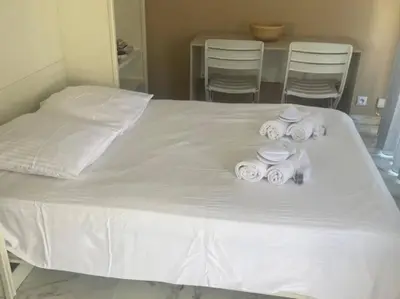 a bed with white towels and chairs in a room at Studio AC with Balcony by Olidesi in Cannes