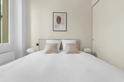 a white bedroom with a white bed with two pillows at LB Vacation Rentals I Renovated Apartment Min from Beach and Palais in Cannes