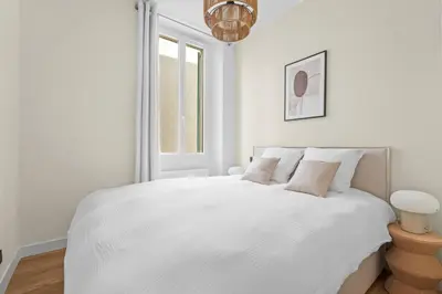 a white bedroom with a white bed with a window at LB Vacation Rentals I Renovated Apartment Min from Beach and Palais in Cannes
