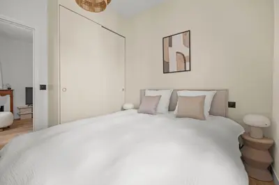 a white bedroom with a large white bed with pillows at LB Vacation Rentals I Renovated Apartment Min from Beach and Palais in Cannes