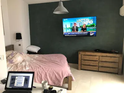 a bedroom with a bed and a tv on a wall at Quiétude in Cannes
