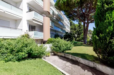 an apartment building with a grassy yard in front of a building at Studio très spacieux et Design LE BELLA Climatisé in Cannes
