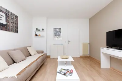 a white living room with a couch and a tv at Studio très spacieux et Design LE BELLA Climatisé in Cannes