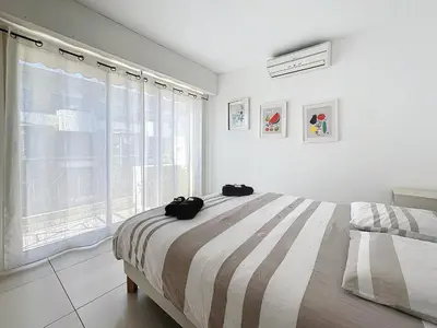 a bedroom with a bed and a large window at 57m2 - 2 chambres, terrasse, Croisette-Martinez in Cannes