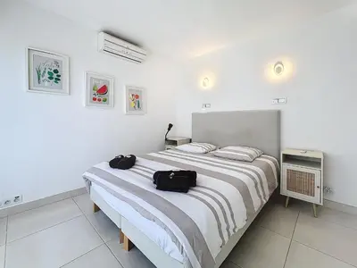 a white bedroom with a large bed with two bags on it at 57m2 - 2 chambres, terrasse, Croisette-Martinez in Cannes