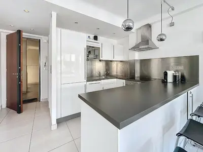 a kitchen with white cabinets and a black counter top at 57m2 - 2 chambres, terrasse, Croisette-Martinez in Cannes