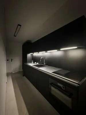 a black kitchen with a sink and a stove at Appartement Design élégant in Le Cannet