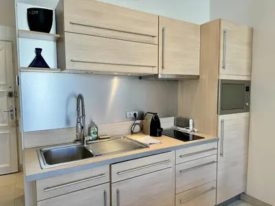 a kitchen with wooden cabinets and a sink at Cannes La Croisette - Joli studio au calme coté jardin in Cannes