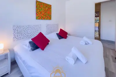 a white bed with red and blue pillows on it at LE SURCOUF Appartement by 4 By SUNSET in Le Cannet