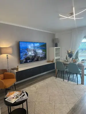 a table with a bowl of fruit and two glasses of wine at Premium 80sqm Apartment Opposite Martinez, Steps from Congress Center in Cannes