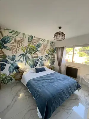 a bedroom with a large bed with blue sheets and plants at Oasis by L'Oliveraie in Cannes