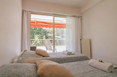 two beds in a room with a large window at Le Navarre By ApiRent #Terrasse #Ascenseur #Wifi in Cannes