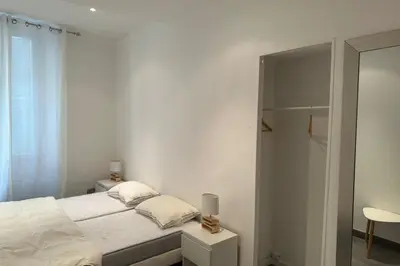 a white bedroom with a bed and a mirror at Charming T2 in the heart of city center in Cannes