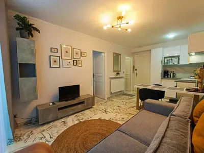 a living room with a couch and a television in it at La Résidence Fleuries - Plage in Cannes