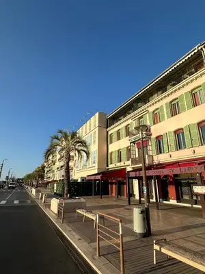 an empty city street with buildings and palm trees at Nice Living Cannes Plage in Cannes