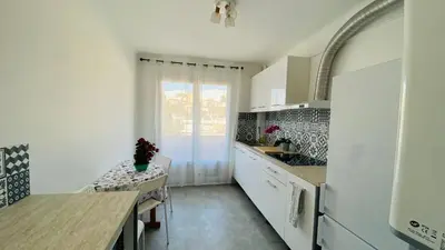 a kitchen with white cabinets and a table and a sink at Joli 3pièces refait à neuf et très bien situé in Cannes
