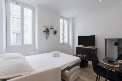 a white bedroom with a bed and a tv at 