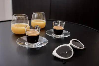 three glasses of coffee and orange juice on a table at 