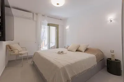 a white bedroom with a bed and a chair at 7 Pradignac by Halldis in Cannes