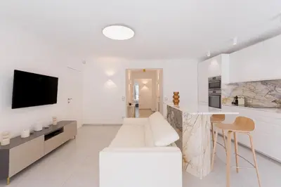 a white living room with a white couch and a kitchen at 7 Pradignac by Halldis in Cannes